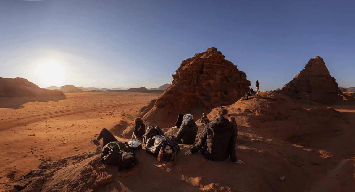 tourists sitting on a hill in the desert